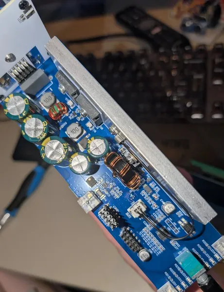 The main blue PCB showing electrolytic capacitors, toroidal inductors, MOSFETs, and aluminium heatsink plate